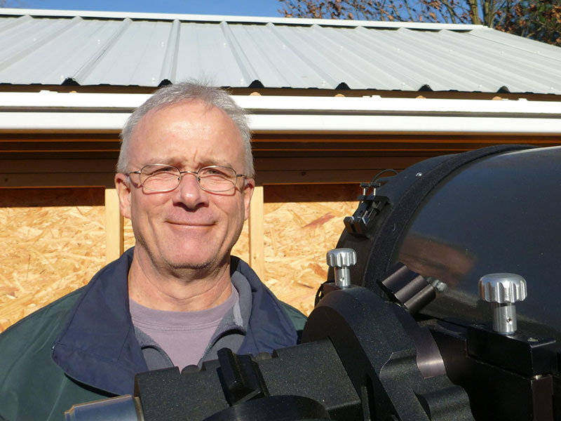 Man smiling next to telescope
