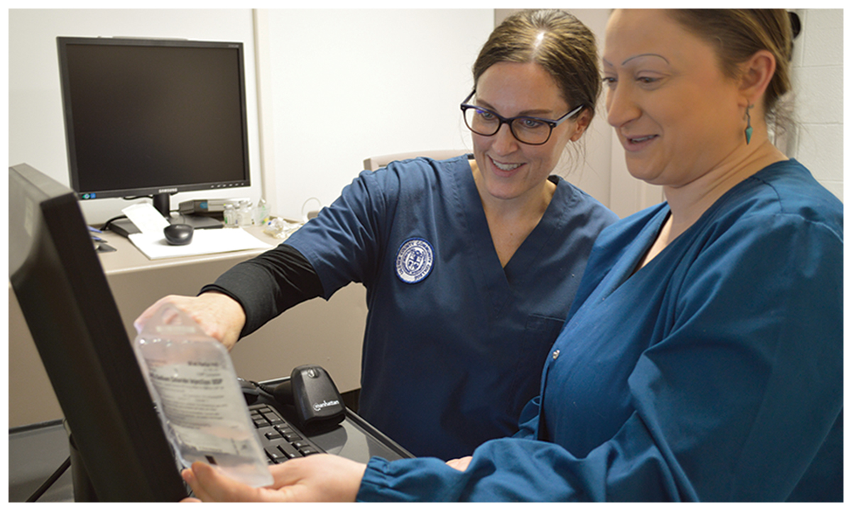 women in scrubs pointing to computer screen