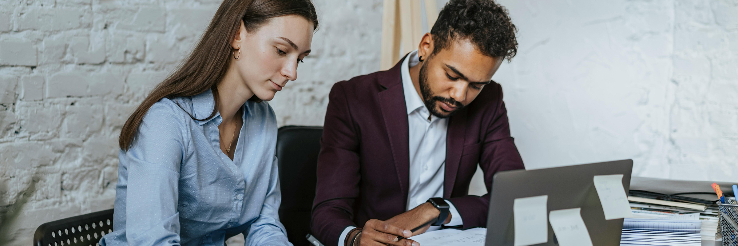 white woman and black man in business clothes, working at desk