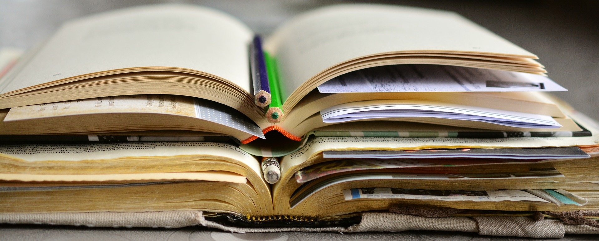 pile of open books with pencils