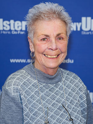 Portrait of Mary Mendola in front of SUNY Ulster backdrop