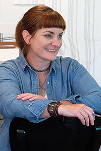 Rita MacDonald artist sitting at desk in studio